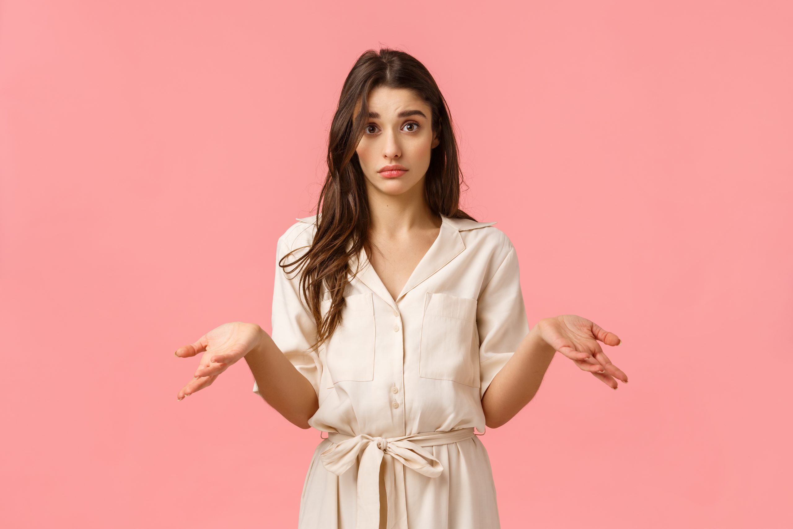 So what, I dont know. Silly and clueless uncertain cute, glamour girl in dress, shrugging and raise hands sideways confused, cant figure out what do, standing pink background unsure